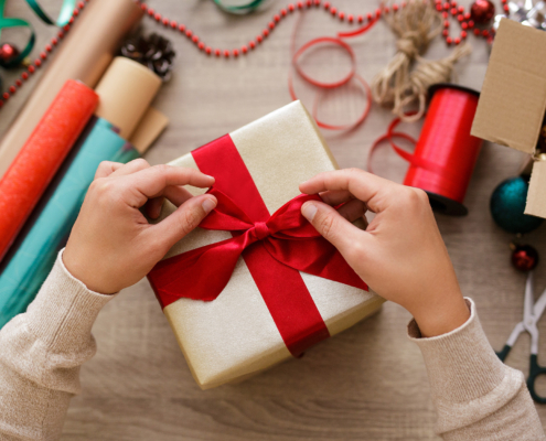 Person putting bow on holiday packaging