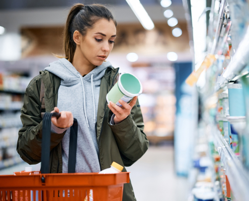 Young woman reads product label while buying diary product in supermarket