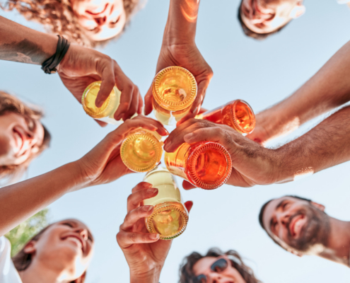 bottom view of group of happy young people clinking bottles of beer